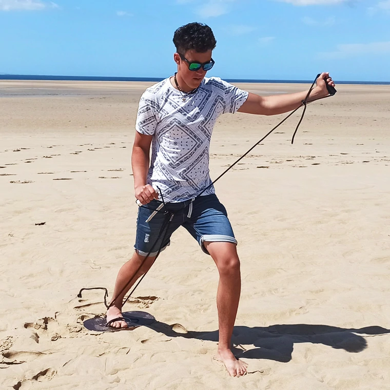Mann trainiert am Strand mit Rope Plate